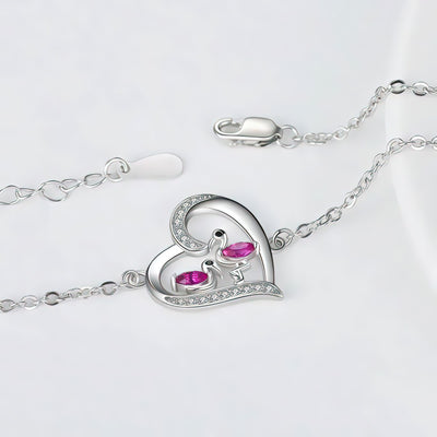 Silver flamingo bracelet with a heart-shaped clasp featuring pink gemstones on a light gray background