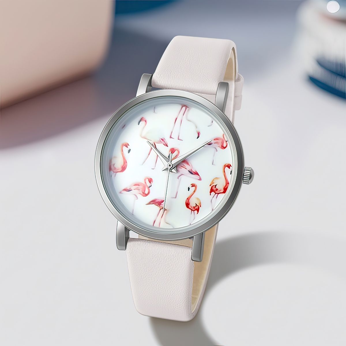 Watch with flamingo design on the dial and beige strap on a light gray background