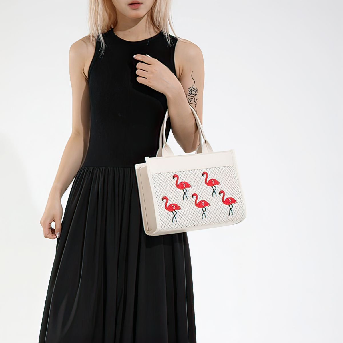 Woman holding a white handbag with flamingo designs against a white background