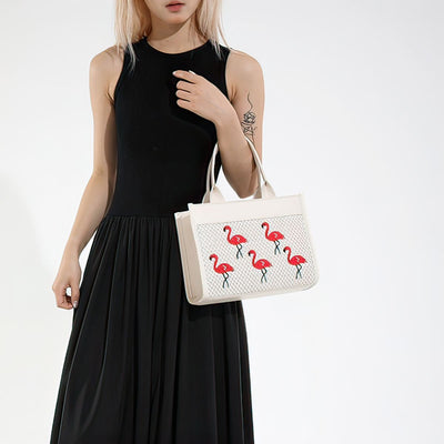 Woman holding a white handbag with flamingo designs against a white background