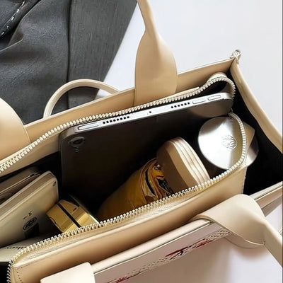 Beige handbag with a phone and bottle inside, on a light gray background