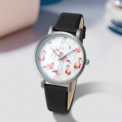 Watch with flamingo design on the dial and black leather strap on a light gray background