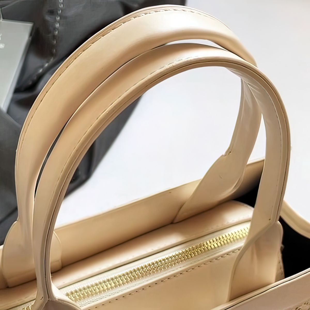 Close-up of a beige handbag with a gold zipper.