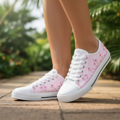 White sneakers with pink flamingo pattern worn outdoors on a wooden floor.