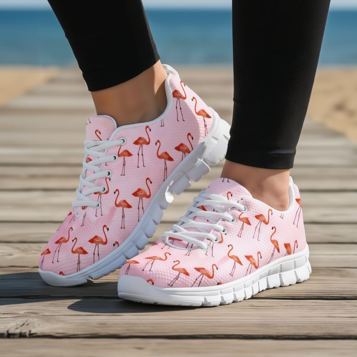 Pink flamingo-patterned sneakers on a wooden deck with a blurred beach background