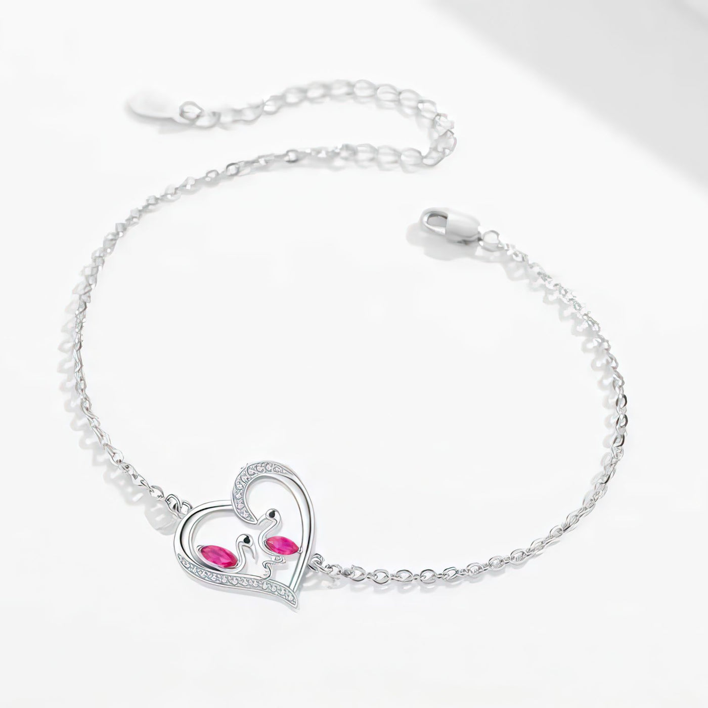 Silver flamingo bracelet with a heart-shaped clasp featuring red gemstones on a white background